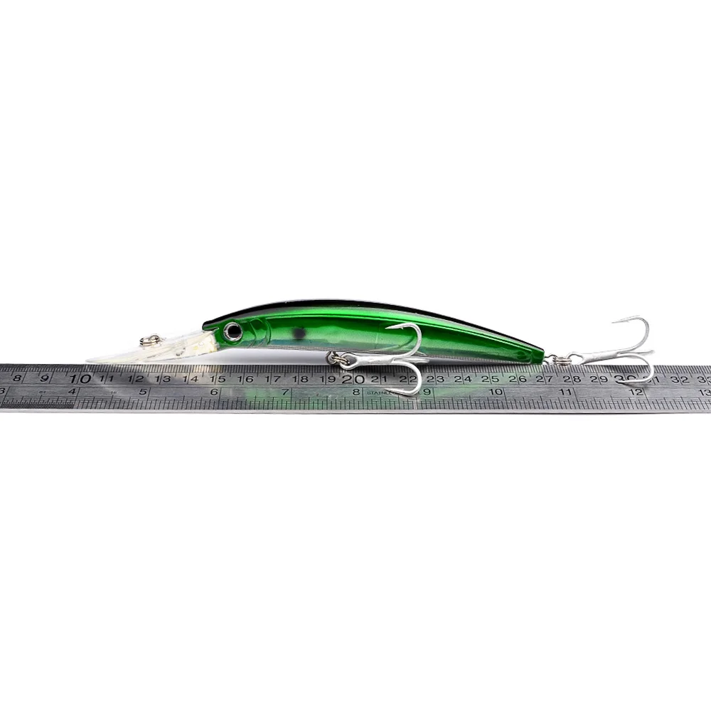 Green and black minnow lure placed next to a ruler showing approximate length