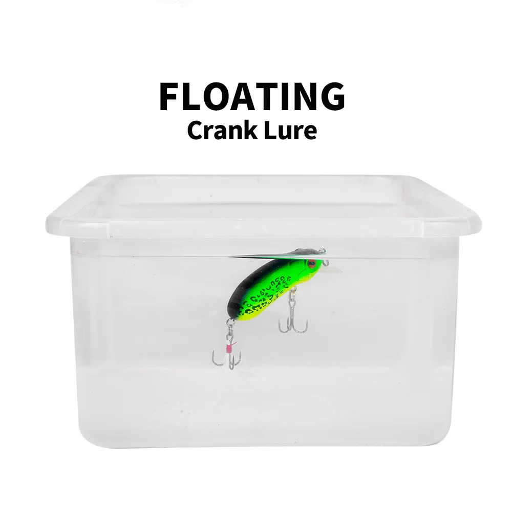 A green-black floating crank lure shown suspended in water inside a transparent container, demonstrating its buoyancy.